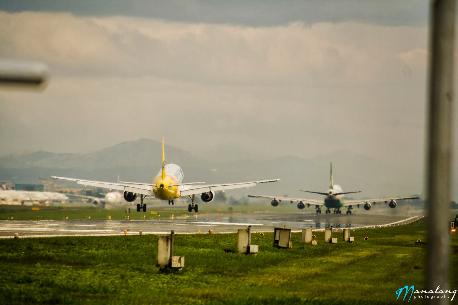 A Cebu Pacific Airbus A320 lands as an EVA Air Boeing 747-400 departs at the Ninoy Aquino International Airport.